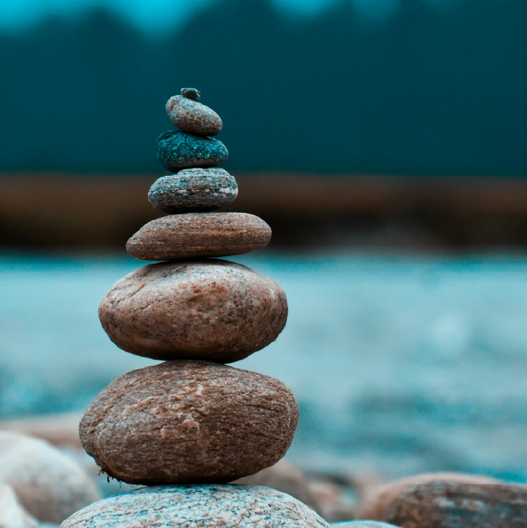 in front of a river, a stack of six small stones balances.